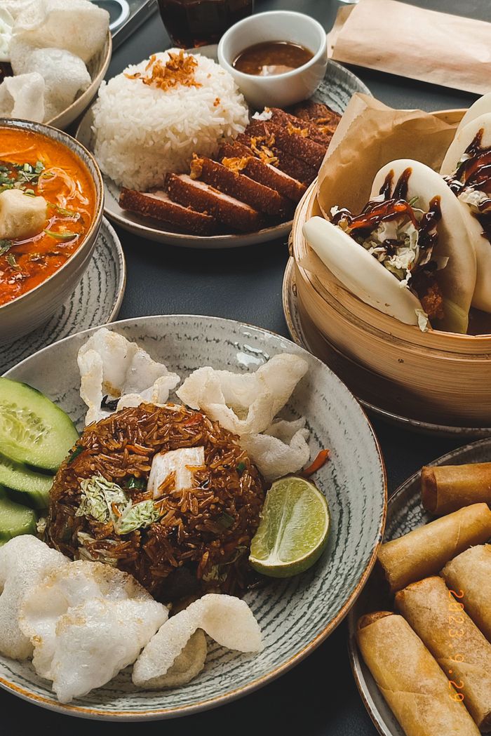 A vibrant spread of assorted Asian dishes including dim sum, rice, and spring rolls.