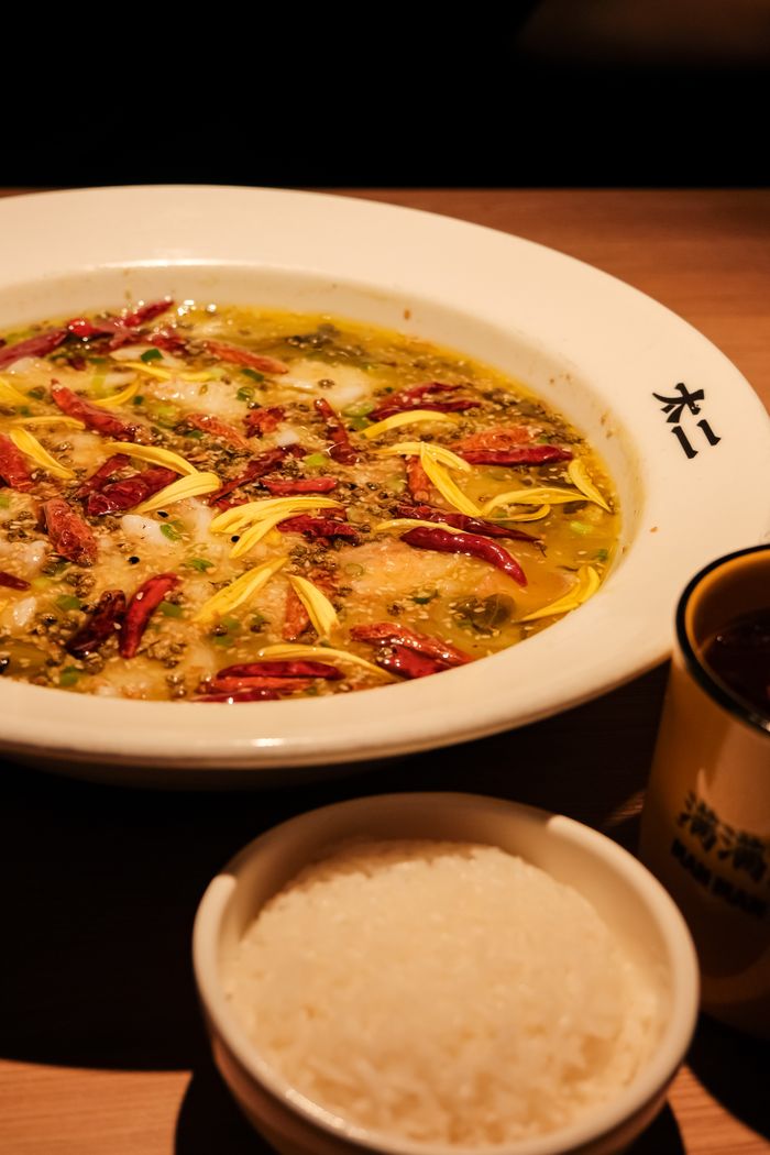 our-journey-02 Delicious spicy Asian fish soup served with rice, featuring vibrant chili peppers and herbs.