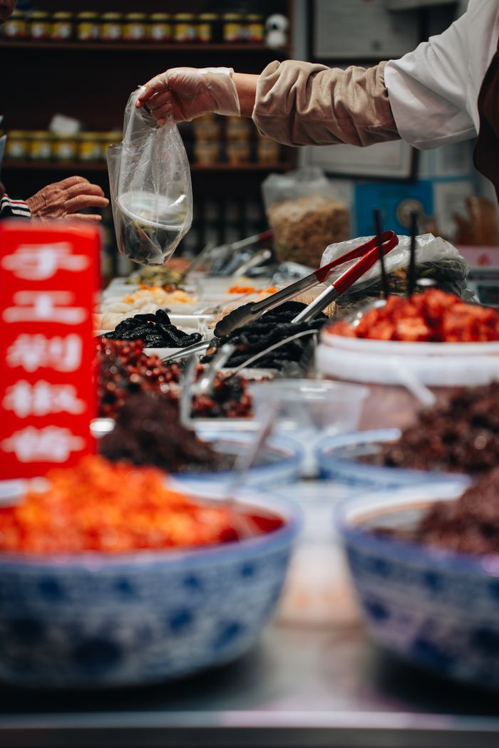 Colorful bowls of spices and ingredients at a bustling street food market in Shanghai.